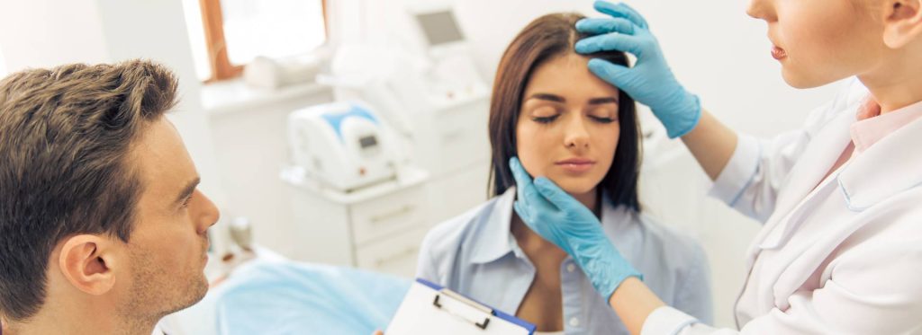 A woman receiving a facial examination in a clinic.