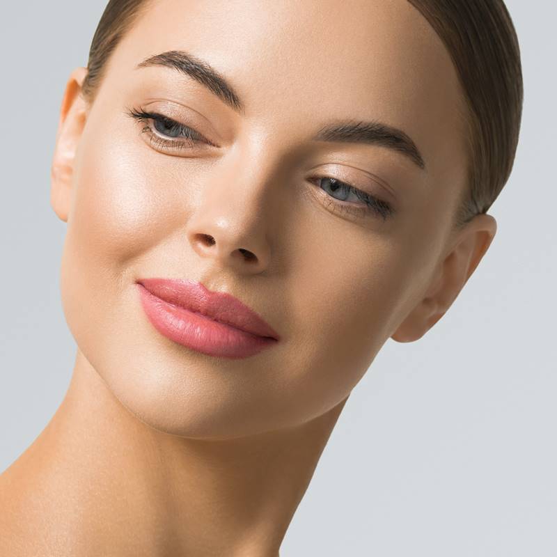 Portrait of a smiling woman with smooth skin and natural makeup.