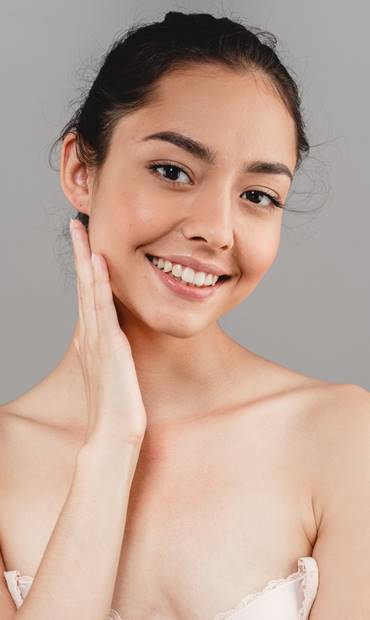 Smiling woman touching her cheek with radiant skin.