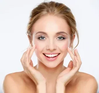 Smiling young woman with clear skin touching her face.