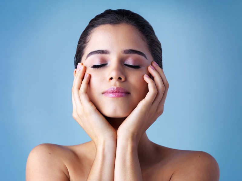 A woman with eyes closed gently touching her face, showcasing calmness and skincare.