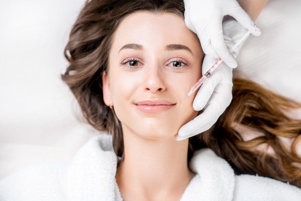 A woman receiving a facial injection from a gloved professional.