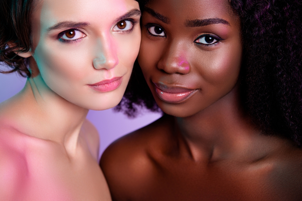 Close-up of two women with different skin tones posing together.