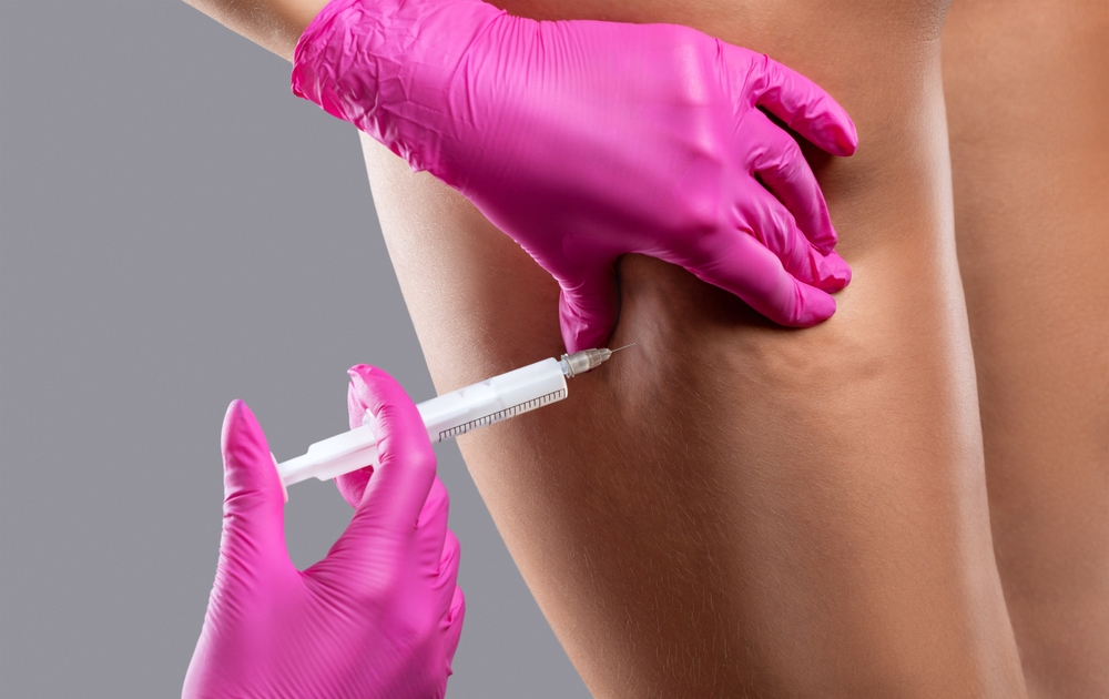 A person receiving an injection in the upper arm with pink gloves.