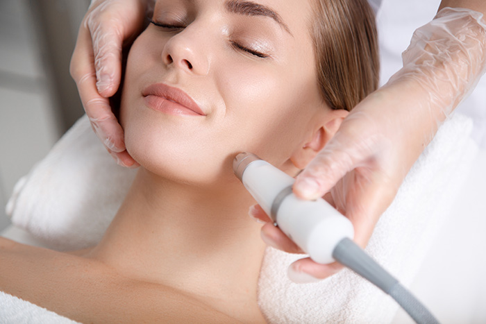 Woman receiving a gentle facial treatment with a skincare device.