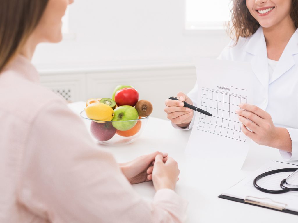 A nutritionist consulting a patient with healthy fruits on the table.