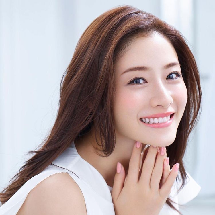 Smiling woman with long hair and radiant skin.