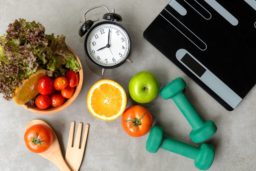Healthy lifestyle items: fresh fruits, salad, and dumbbells.