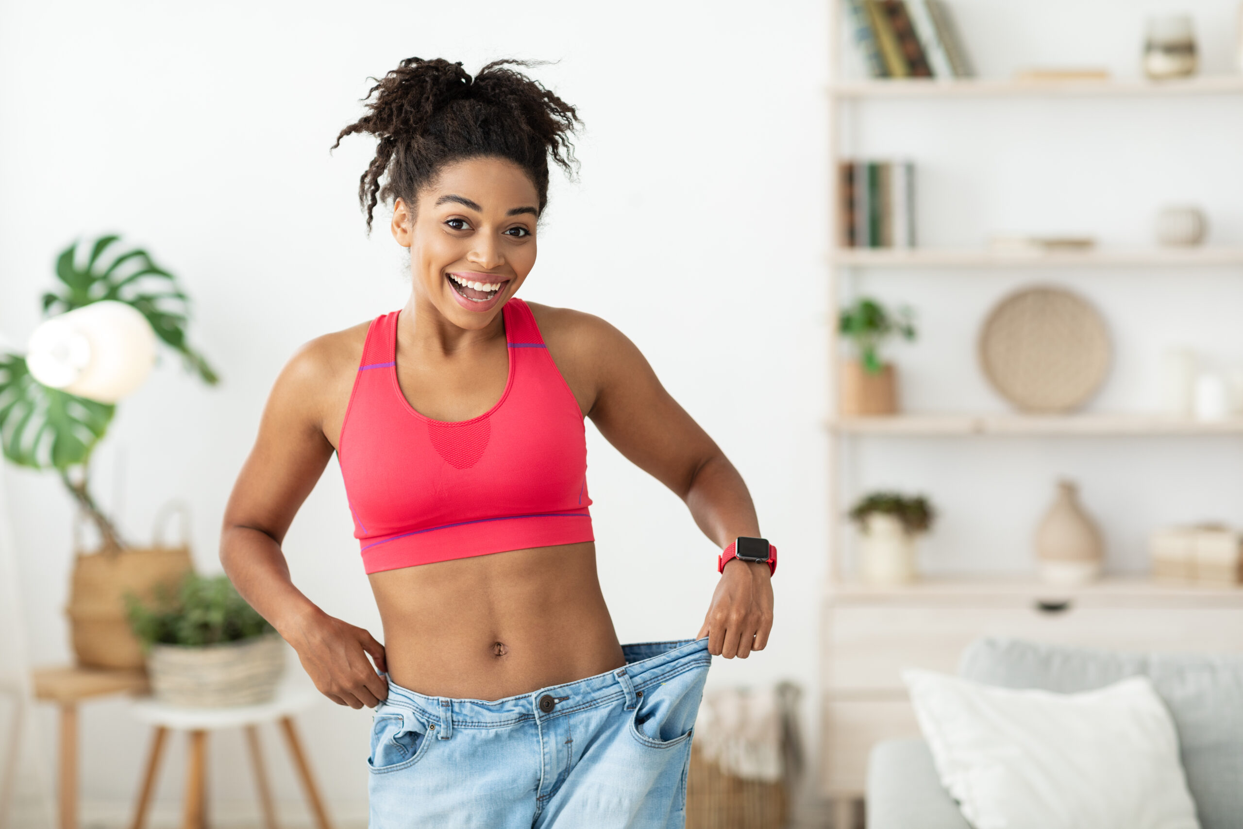 Happy woman shows weight loss by fitting into loose jeans.
